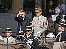 Prezident Emanuel Macron jel vestoje v oteveném vojenském voze v doprovodu...