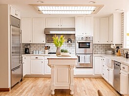 V dom je prostorná kuchy v klasickém stylu s bílými skíkami a nerezovými...