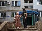 Policista pomáhá starí en ped jejím domem v Kramatorsku, který byl pokozen...