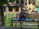 ena si te na lavice ped sídlitm v Mariupolu na Ukrajin. (15. ervence...