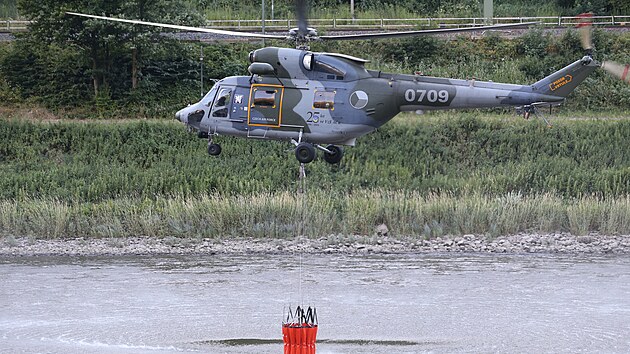 Vrtulník zasahující v Národním parku České Švýcarsko u Hřenska na Děčínsku nabírá vodu do vaku z řeky Labe. (24. července 2022)