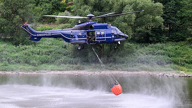 Vrtulnk nabr vodu z Labe, aby uhasil lesn por v Nrodnm parku Sask vcarsko. (27. ervence 2022)