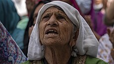 Starší kašmírská žena se modlí zatímco hlavní kněz během zvláštních modliteb k...