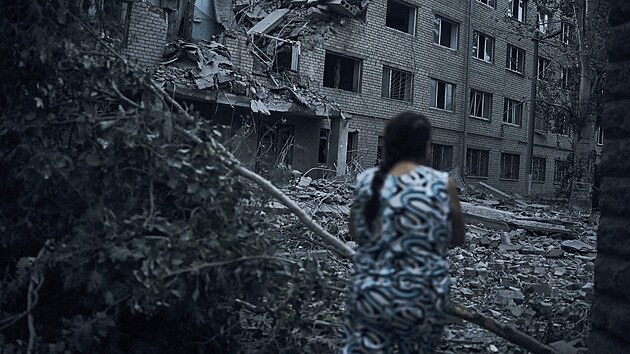 Ukrajinka prochází mezi troskami obytné budovy po nočním ostřelování v Mykolajivu na Ukrajině. (2. srpna 2022)