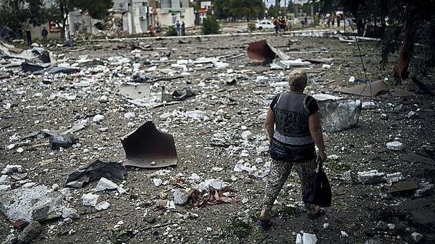Ukrajinka prochází mezi troskami obytné budovy po nočním ostřelování v Mykolajivu na Ukrajině. (3. srpna 2022)