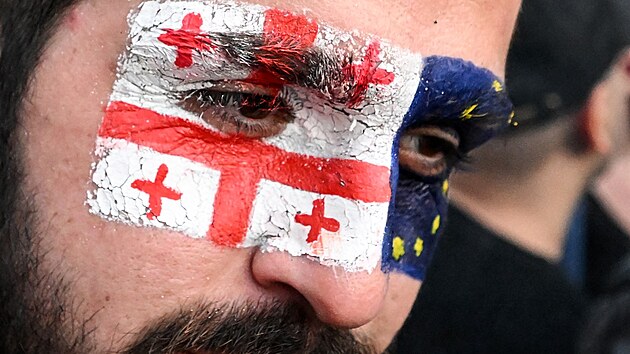 Muž s vlajkami Evropské unie a Gruzie na tváři během shromáždění na podporu členství Gruzie v Evropské unii (3. července 2022)
