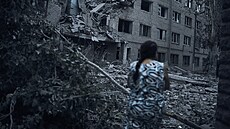 Ukrajinka prochází mezi troskami obytné budovy po noním ostelování v...