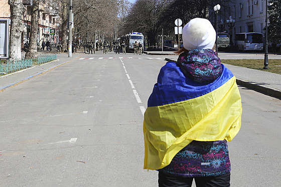 ena zahalená ukrajinskou vlajkou stojí ped ruskými vojáky pi protestu proti...