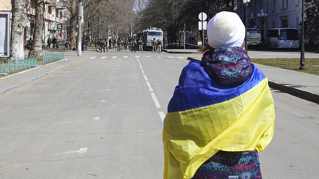 ena zahalená ukrajinskou vlajkou stojí ped ruskými vojáky pi protestu proti...