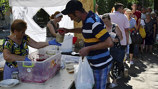 Lid dostvaj jdlo na distribunm mst humanitrn pomoci v Zporo na Ukrajin. (9. srpna 2022)