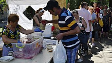 Lidé dostávají jídlo na distribuním míst humanitární pomoci v Záporoí na...