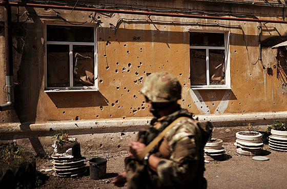 Ukrajinský voják prochází kolem rapnel na zniené budov asi 6 km od frontové...