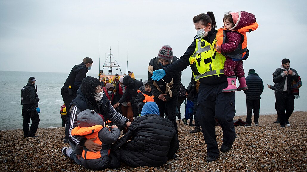 lenka britské pohraniní jednotky pomáhá dtem migrant na plái v Dungeness....