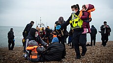 Členka britské pohraniční jednotky pomáhá dětem migrantů na pláži v Dungeness....
