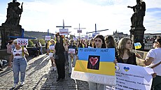 Asi �edesát lidí se se�lo v ned�lní podve�er na Karlov� most�, aby protestem s názvem K�í�ová cesta sponzor� ruské ekonomiky upozornilo na firmy, které i p�es ruskou okupaci Ukrajiny stále z�stávají na ruském trhu. (21. srpna 2022)