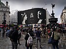 Lidé se zastavují u billboardu k poct královny Albty II. na Piccadilly...