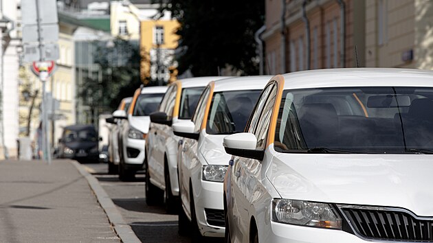 Taxi. White cars with a yellow stripe stand in a row on a street in the city...