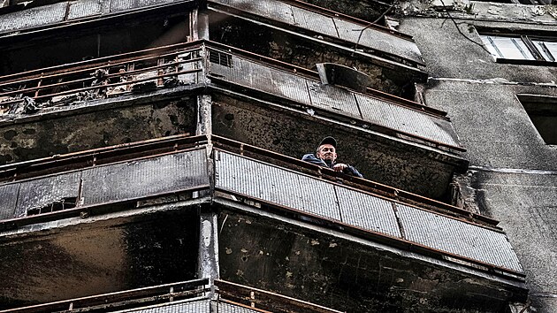 Muž shlíží s balkonu zasaženého domu. Charkovská čtvrt Saltivka, je jednou z nejvíce poškozených obytných oblastí. (6. září 2022)