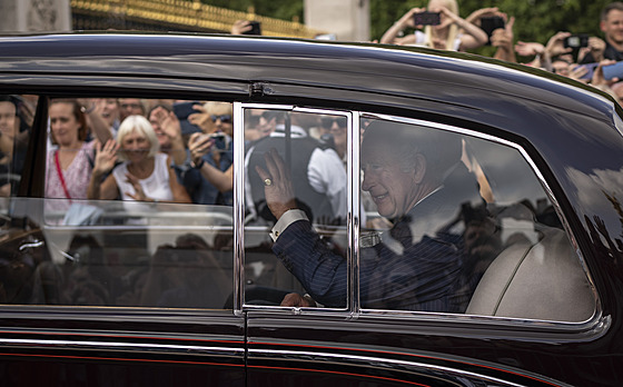 Král Charles III. pijídí do Buckinghamského paláce a zdraví pihlíející....