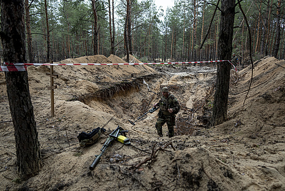 Ukrajinský voják pouívá detektor ke kontrole masového hrobu v nedávno...