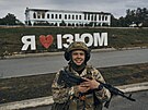Voják ukrajinské armády se usmívá ped nápisem v osvobozeném mst, který íká...