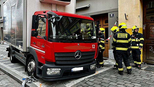 Hasii vyprouj nkladn vz, kter se propadl do chodnku v Blehradsk ulici v Praze. (12. z 2022)