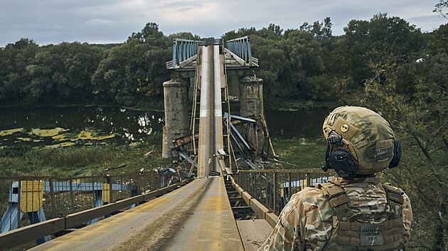Voják ukrajinské armády se dívá na zničený most v osvobozeném městě Izjum. (14. září 2022)