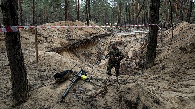 Ukrajinsk vojk pouv detektor ke kontrole masovho hrobu v nedvno znovudobyt oblasti Iziujum. V hrobu se nachz tla ukrajinskch vojk, kte padli bhem boj na zatku vlky. (15. z 2022)