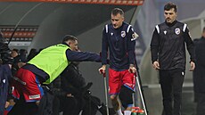 Zraněný Jan Sýkora se vrací na lavičku o berlích s obvázaným kolenem.