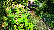 Kamenné chodní�ky lemují hust� rostoucí trvalky.