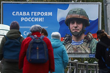 Obyvatelé Petrohradu stojí ped plakátem vojáka s nápisem "Sláva ruským...