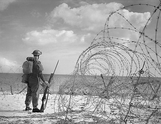 Britský voják hlídkující na pláži