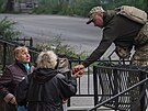 Ukrajinský voják dává jablka enám z osvobozeného msta Izjum.(16. záí 2022)
