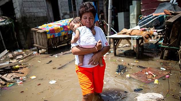 Obyvatelka s dttem na Filipnch po kod napchan tajfunem Noru. (27. z 2022)