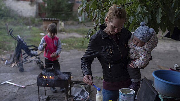 Margarita Tkaenkov ped svm domem v Izjumu pipravuje dtem na ohni jdlo. (25. z 2022)