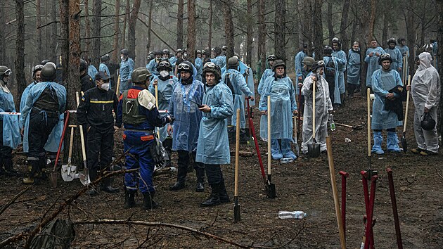 Ukrajinští záchranáři, policisté a experti při exhumačních pracích na masovém hrobu v osvobozeném městě Izjum. (16. září 2022)