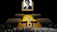 Portrét bývalého premiéra Japonska inzó Abeho visí nad pódiem jeho státního...