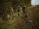 Ukrajintí vojáci procházejí kolem tla vesniana, kterého zabila ruská mina u...