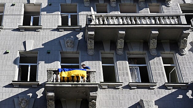 Okna jsou sice vymlcen, ale vlajka nesm chybt. Kyjevan po ruskch tocch vyvuje na balkon ukrajinsk barvy. (10. jna 2022)