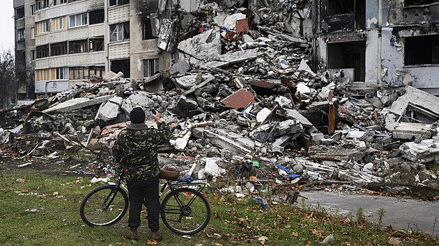 Muž si fotografuje zničený panelový dům na charkovském předměstí Saltivka, 8. listopadu 2022, Charkov, Ukrajina.