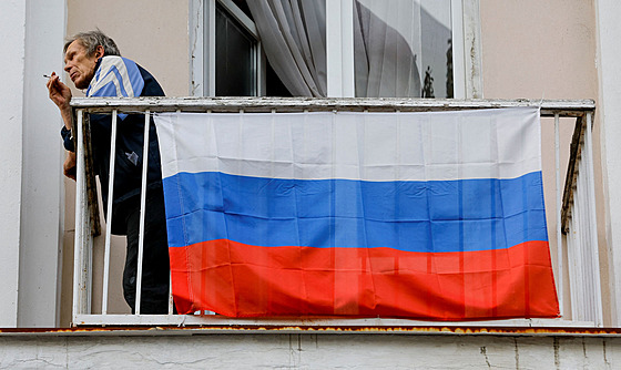 Mu s ruskou vlajkou na balkon domu v Doncku