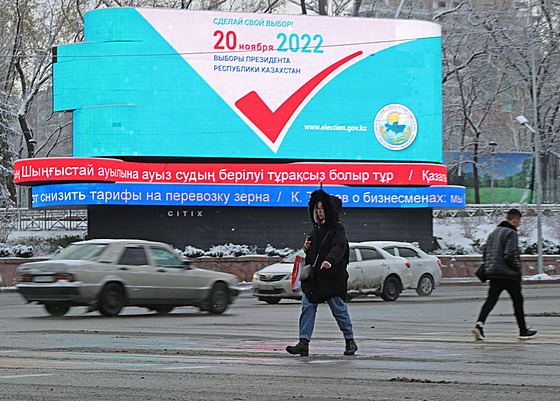 Lidé v Almaty procházejí kolem tabule informující o nadcházejících...