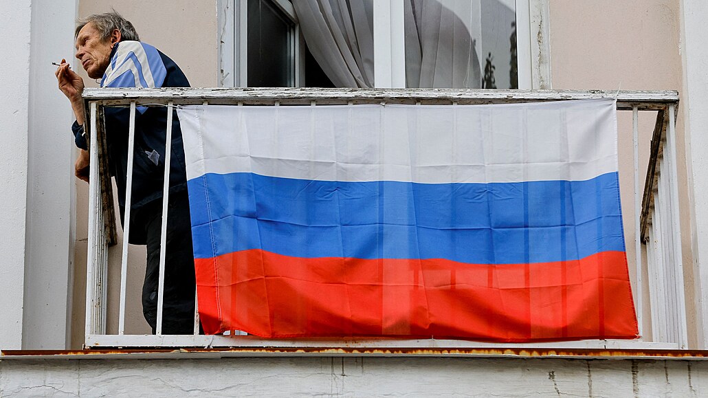 Muž s ruskou vlajkou na balkoně domu v Doněcku