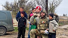 Ukrajinský voják se fotí s dtmi v osvobozeném Chersonu. (11. listopadu 2022)