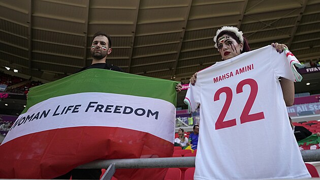 Íránský fanoušek při zápase MS v Kataru proti Walesu drží vlajku s nápisem Žena, Život, Svoboda, který se stal heslem protivládních protestů. Íránská fanynka připomíná smrt 22leté Mahsí Amíníové, jejíž násilná smrt protesty zažehla.