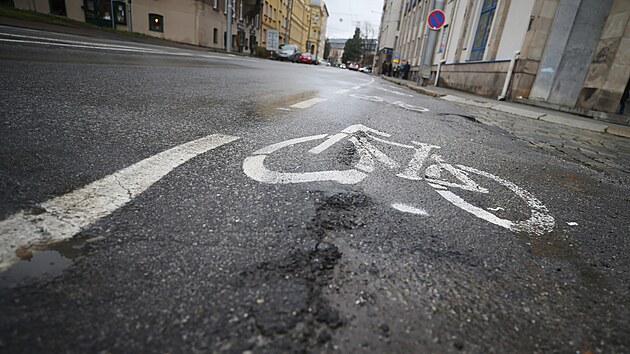 Cyklista v cyklopruhu musí u DKO počítat se záludnostmi: jsou zde propadající se kanály, díry v asfaltu, vydutý povrch či čnějící žulové kostky na autobusové zastávce.