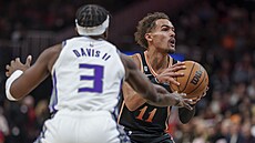 Hv�zda Atlanty Trae Young (11) se pokou�í o p�ihrávku p�es bránícího Terence...