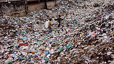 Děti chodí po znečištěné oblasti a sbírají plastové odpadky v Bangladéši.