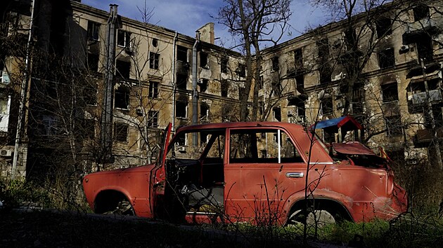 Trosky auta ped rozstlenmi domy v Mariupolu (29. listopadu 2022)