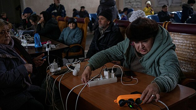 Lidé si nabíjejí elektroniku na nádraží po ústupu ruské armády z Chersonu. Město je po ruském ostřelování bez proudu. (30. listopadu 2022)